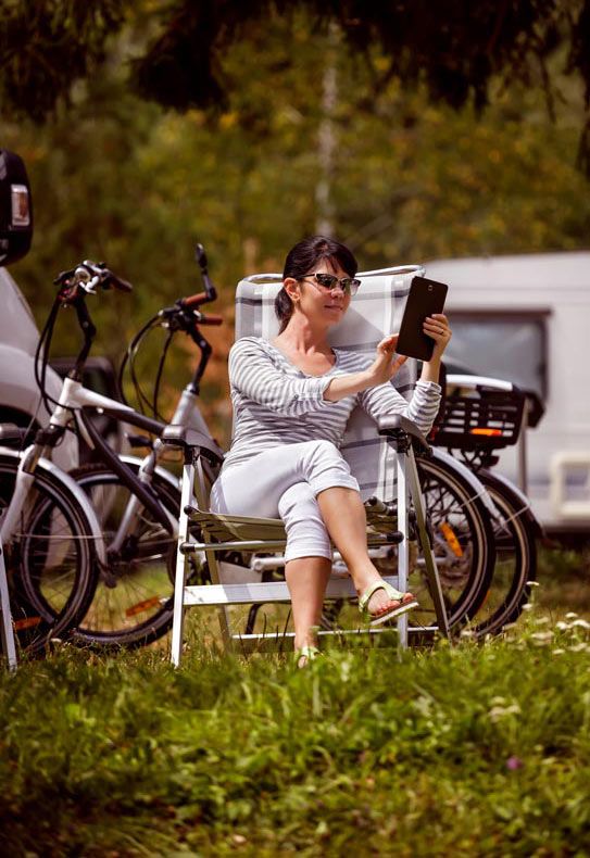 woman-looking-tablet-near-camping-caravan-car-vacation-family-vacation-travel-holiday-trip-motorhome-rv-wi-fi-connection-information-communication-technology-2